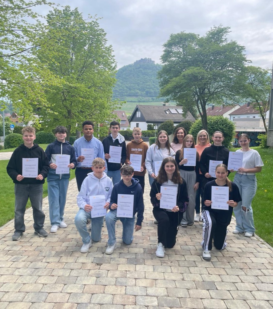 Gruppenbild unserer Streitschlichter. Die Schülerinnen und Schüler halten ihre Urkunde hoch.
