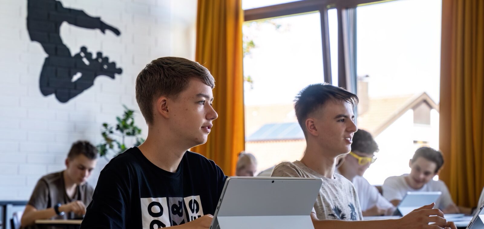 Merhere Jungen in einem Klassenzimmer arbeiten mit Tabletrechnern