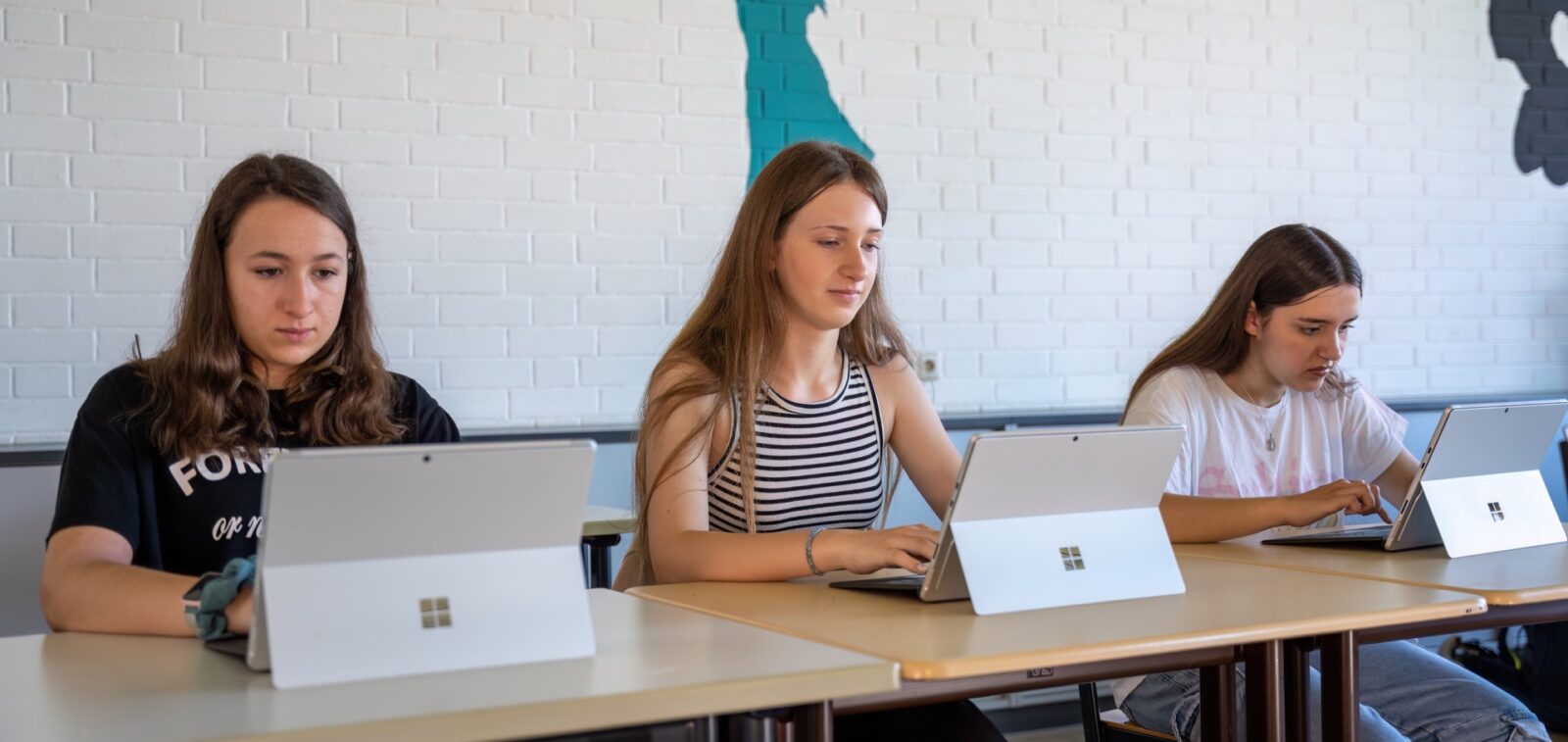 Drei Mädchen sitzen an einem Tisch und arbeiten mit Tabletrechnern
