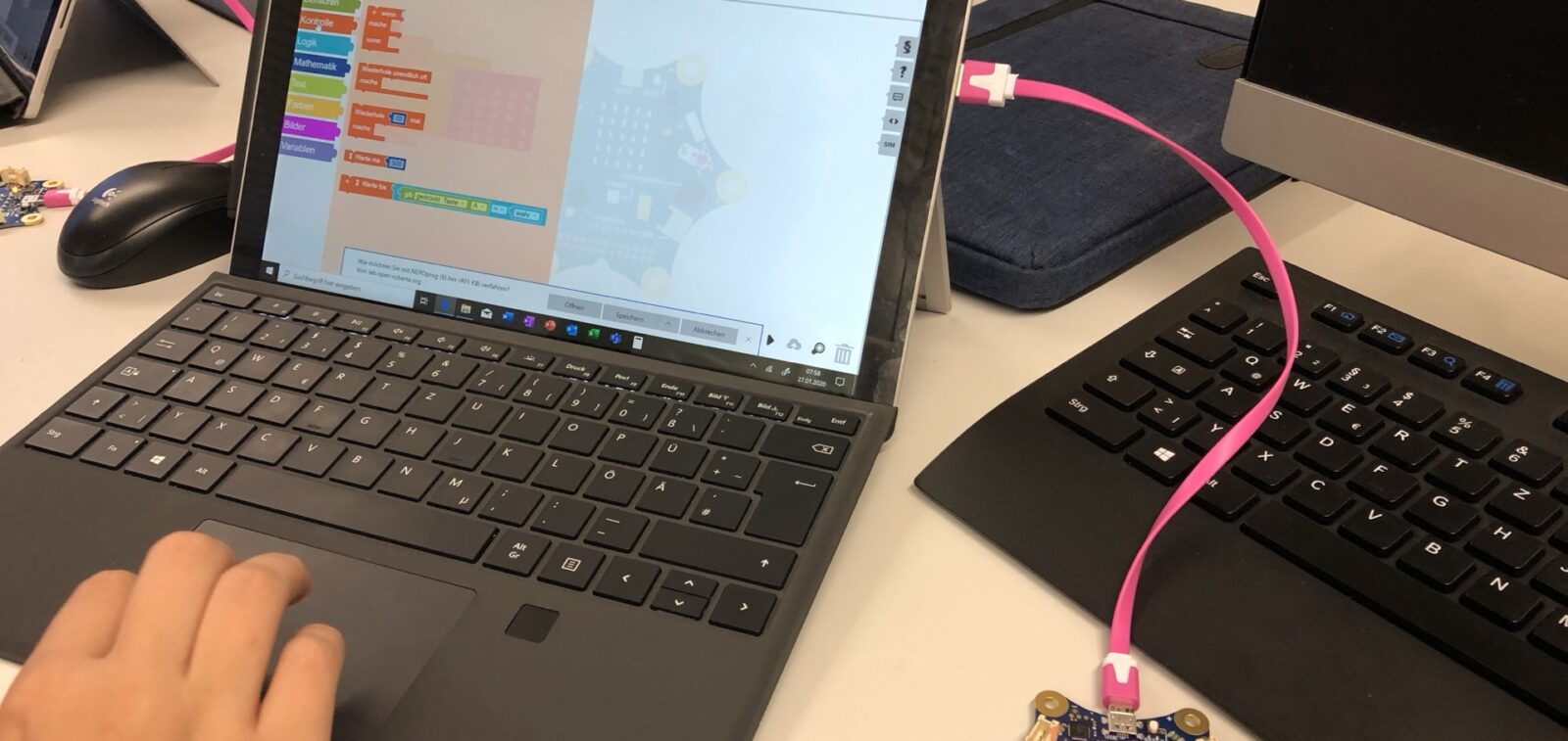 Tisch mit aufgeklapptem laufendem Lapptop